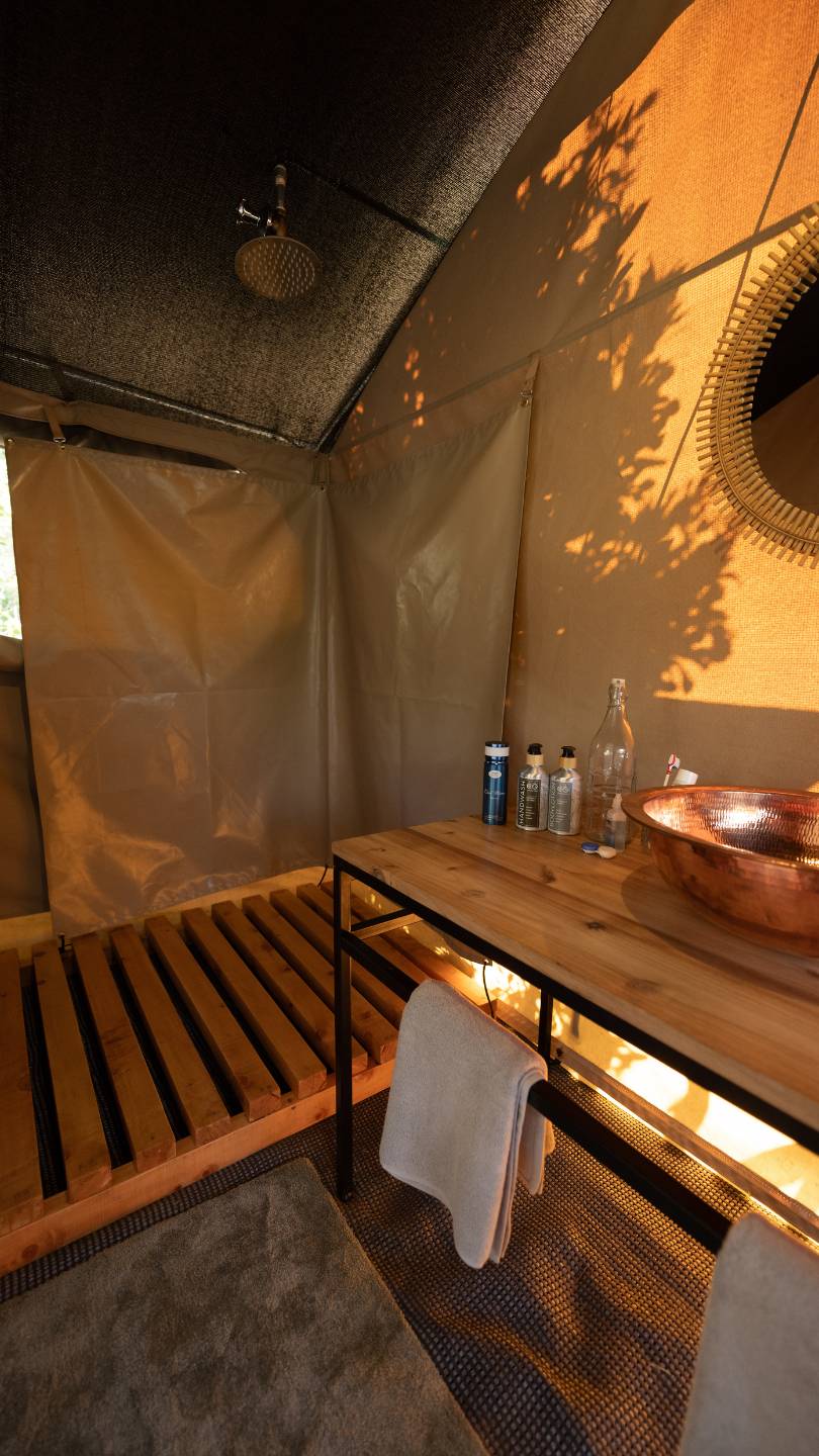 A view of the shower and vanity in a guest safari tent at ENkishui Safari Camp