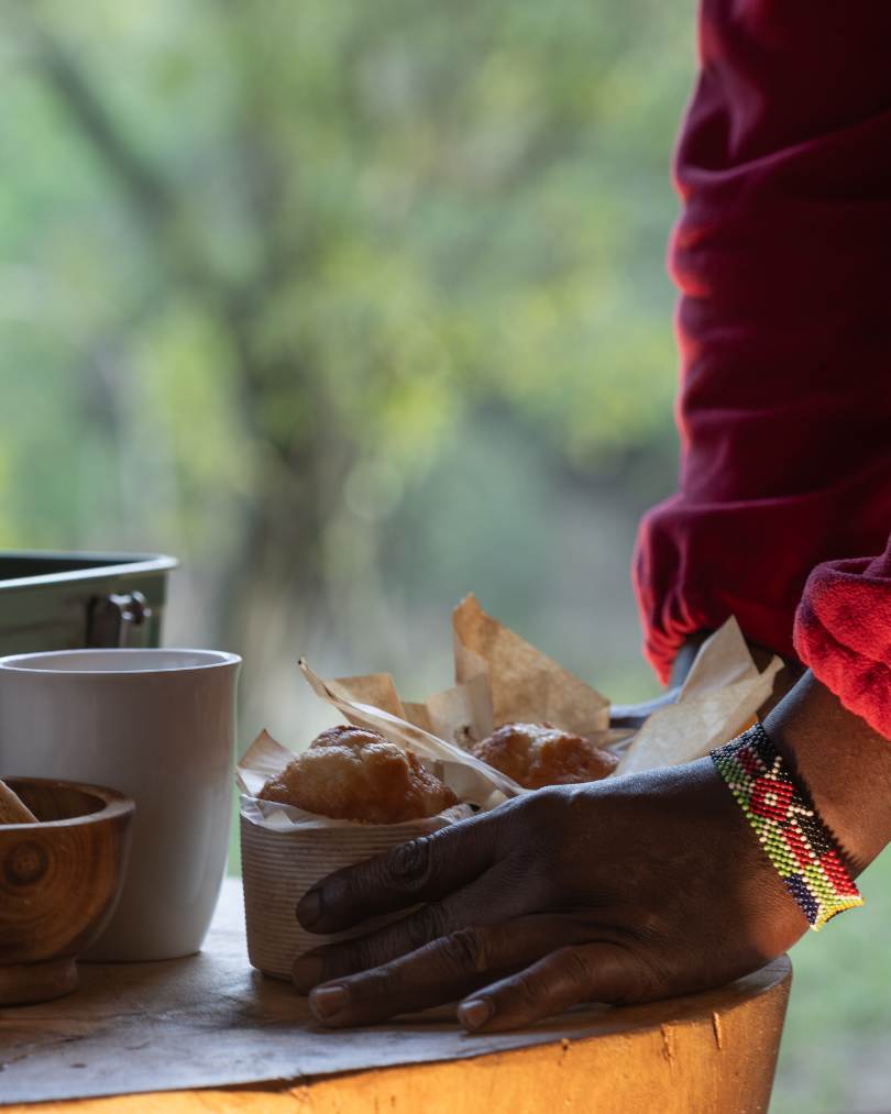 A staff member from Enkishui Safari Camp in the Masai Mara places guests early morning snacks down