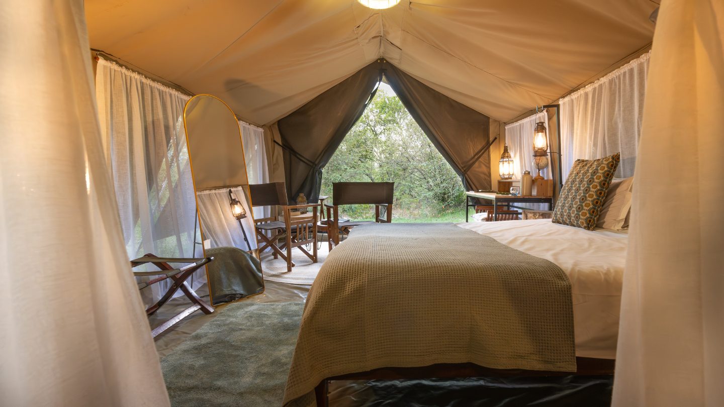 A View from the inside across the bed of a safari tent at enkishui safari camp